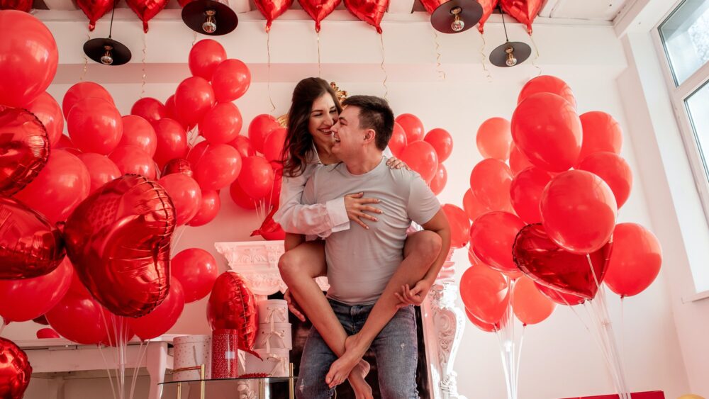 Couple fooling around, looking into each others eyes. Woman sitting on mans back. Valentines day
