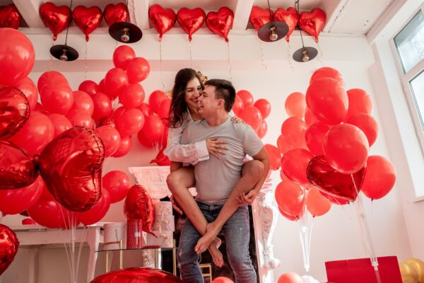 Couple fooling around, looking into each others eyes. Woman sitting on mans back. Valentines day